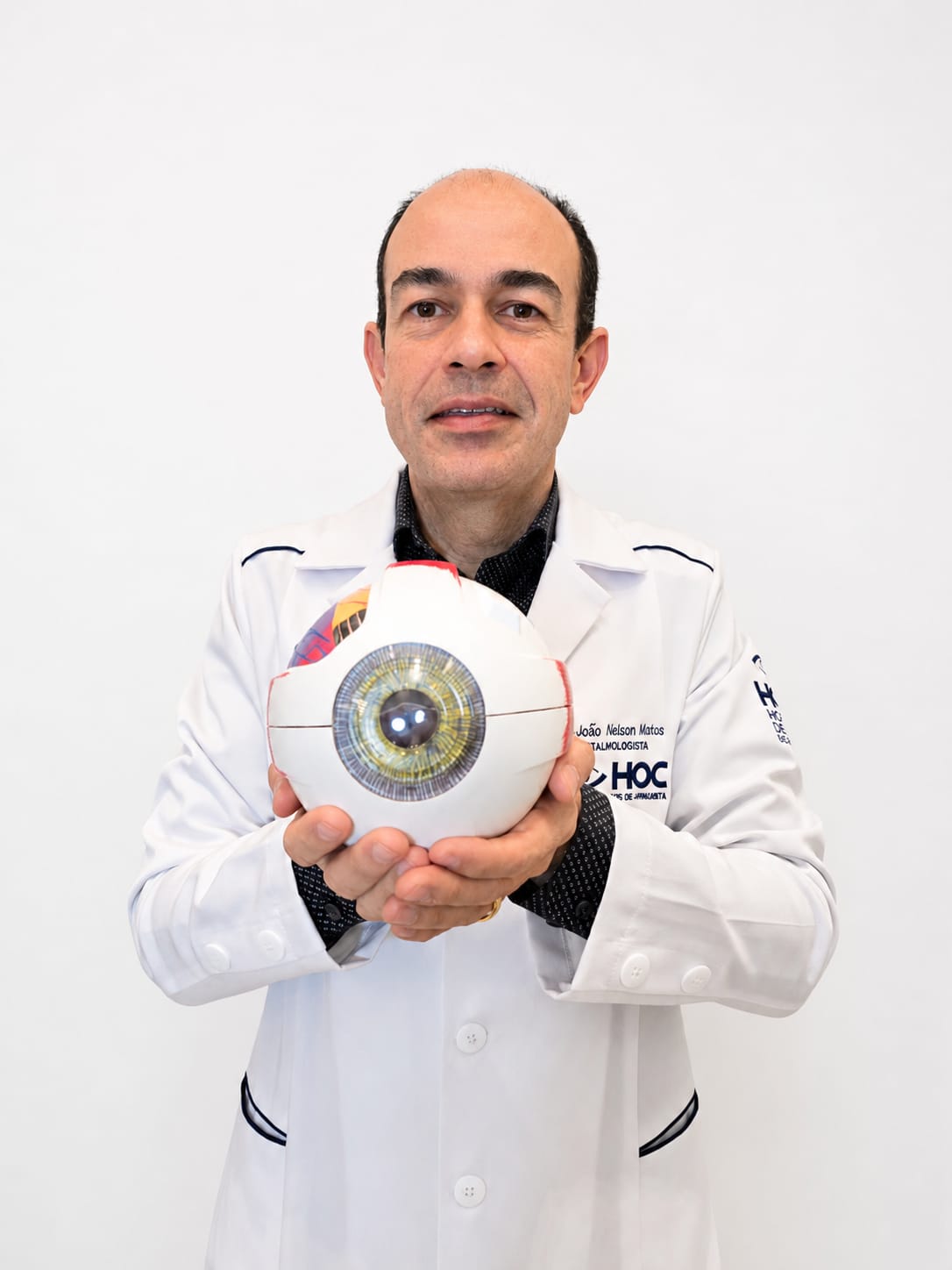 Dr. João Nelson segurando um modelo anatômico do olho humano.